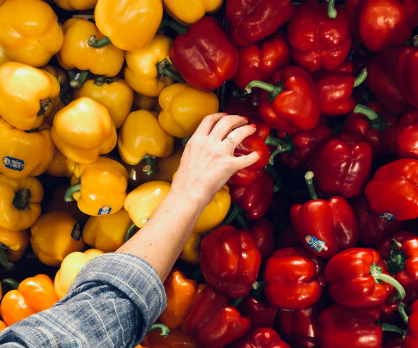 average grocery bill woman reaching for peppers