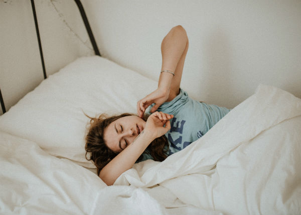 self-care tips woman stretching in bed